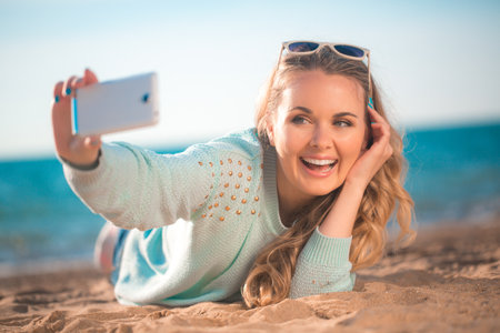 Beautiful girl making selfie on the beachの写真素材