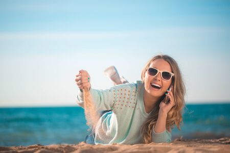 Beautiful girl speaking the phone on the beachの写真素材
