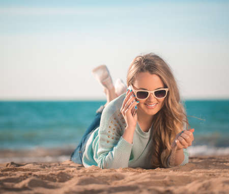 Beautiful girl speaking the phone on the beachの写真素材