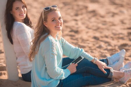 Two girls resting on the autumn beachの写真素材