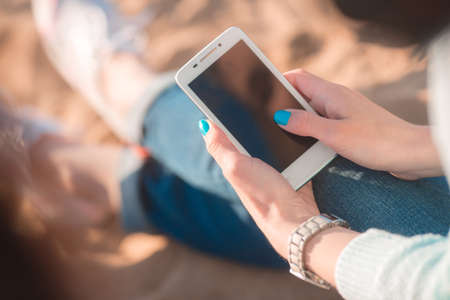 Beautiful girl with the phone in hands on the beach