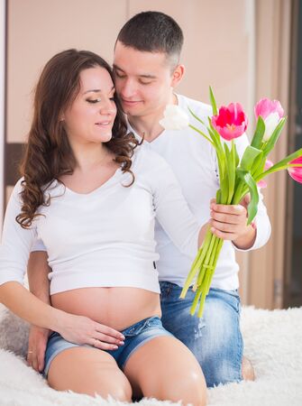 Man and pregnant woman portrait at homeの写真素材