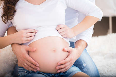 Man and pregnant woman portrait at homeの写真素材