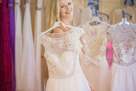 Beautiful young woman  selecting evening dressの写真素材