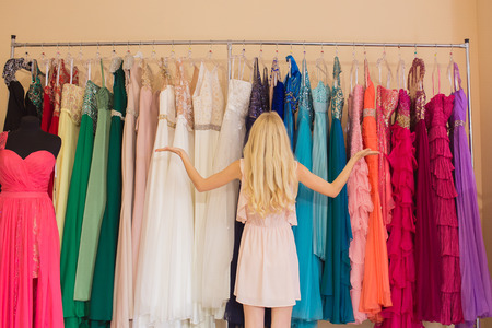 Beautiful young woman  selecting evening dressの写真素材