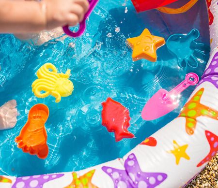 Child swimming pool with plastic toysの写真素材