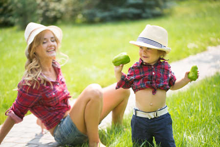 mom and son wiht funny hats sitting on the green grass.の写真素材