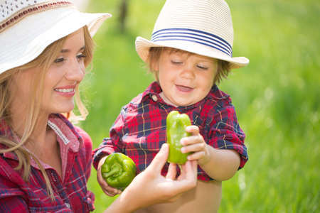 mom and son wiht funny hats sitting on the green grass.の写真素材