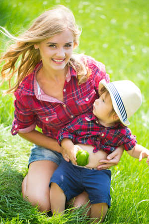 mom and son wiht funny hats sitting on the green grass.の写真素材