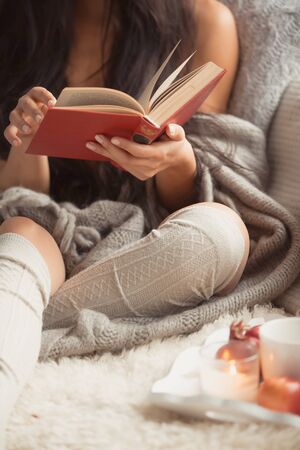 Young beautiful woman reading book at homeの写真素材