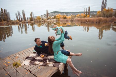 Young family resting on the lake shoreの写真素材