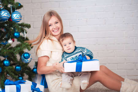 Mother with son holding presents near christmas treeの写真素材