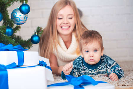 Mother with son holding presents near christmas treeの写真素材
