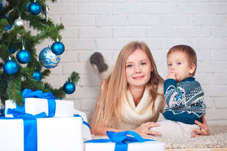 Mother with son holding presents near christmas treeの写真素材