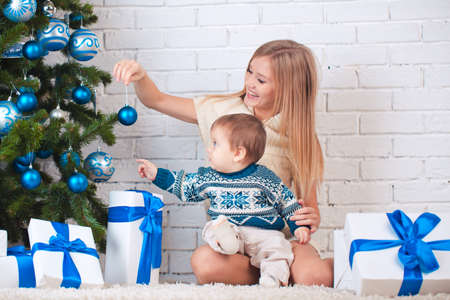 Mother with son holding presents near christmas treeの写真素材