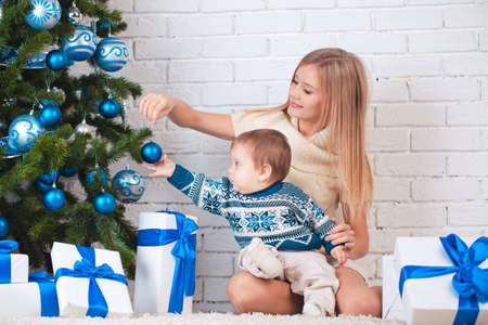 Mother with son holding presents near christmas treeの写真素材