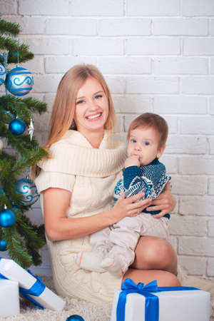 Mother with son holding presents near christmas treeの写真素材