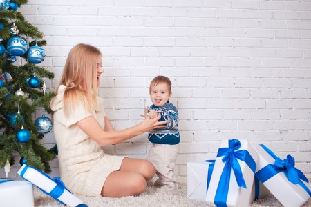 Mother with son holding presents near christmas treeの写真素材
