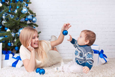 Mother with son holding presents near christmas treeの写真素材