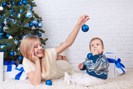 Mother with son holding presents near christmas treeの写真素材