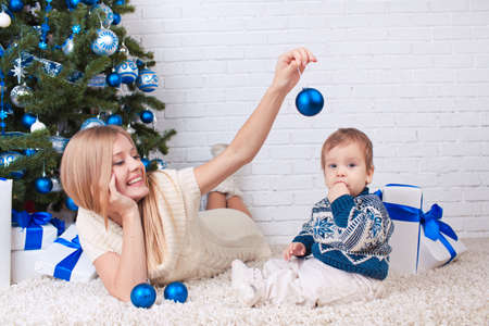 Mother with son holding presents near christmas treeの写真素材