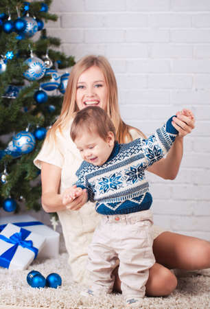 Mother with son holding presents near christmas treeの写真素材