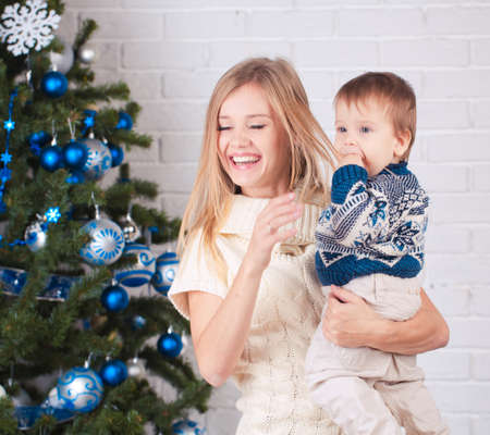 Mother with son holding presents near christmas treeの写真素材