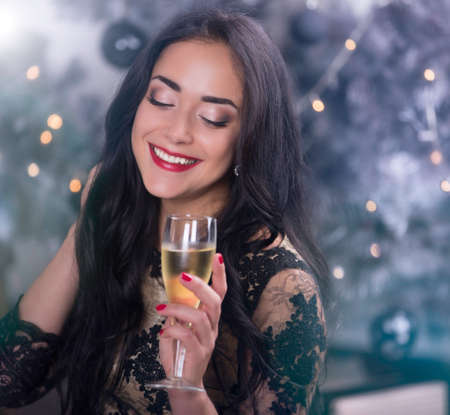 Young beautiful woman at christmas night with glass of wineの写真素材