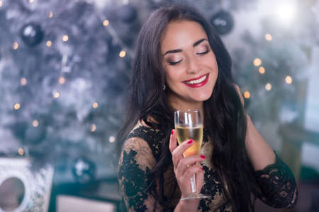 Young beautiful woman at christmas night with glass of wineの写真素材