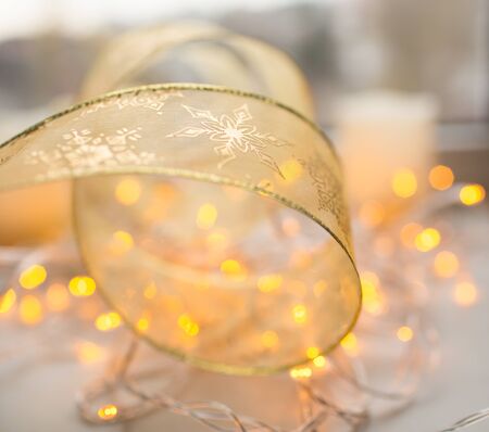 Decoration xmas gold color ribbon with garland lights on backgroundの写真素材