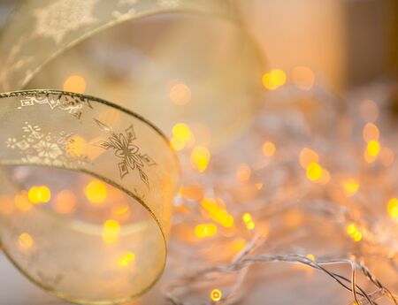 Decoration xmas gold color ribbon with garland lights on backgroundの写真素材