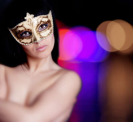 Beautiful brunette girl in mask posing in studioの写真素材