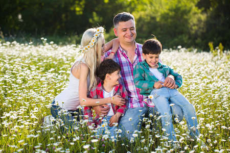 Happy family playing on the chamomile meadowの写真素材