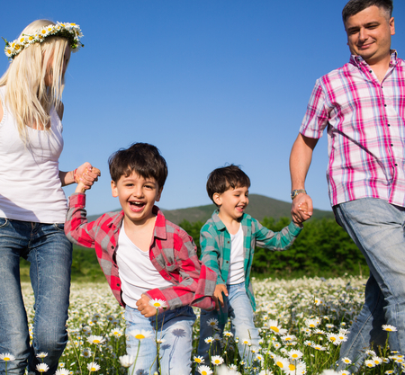 Happy family playing on the chamomile meadowの写真素材