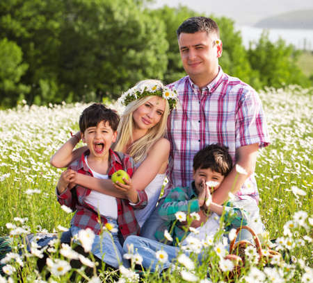 Happy family playing on the chamomile meadowの写真素材