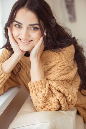 Young beautiful woman in sweater at homeの写真素材