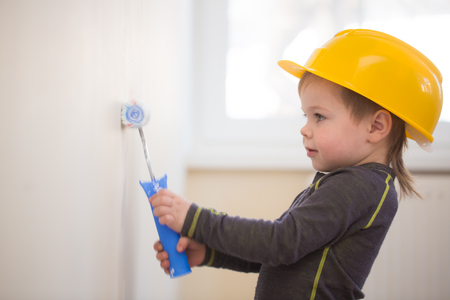 Boy in protective helmet painting the wallの写真素材