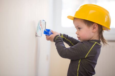 Boy in protective helmet painting the wallの写真素材