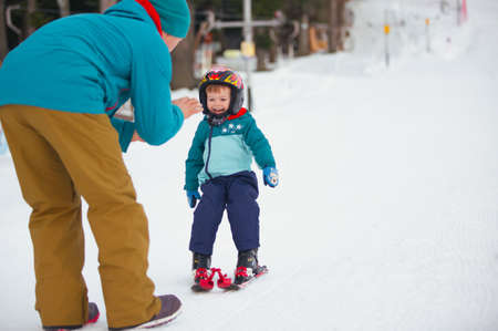 Beautiful young dad and his toddler boy, skiing in the mountainsの写真素材