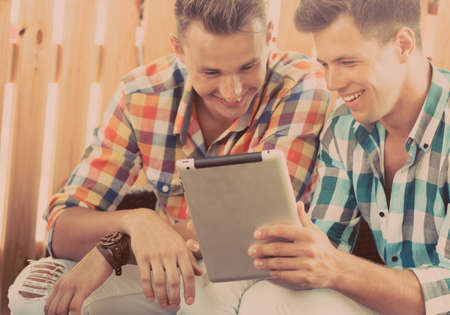 Two friends sitting at the cafe and looking at tabletの写真素材