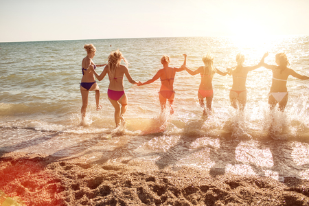 Six girls  jumping on beach at sunset.の写真素材