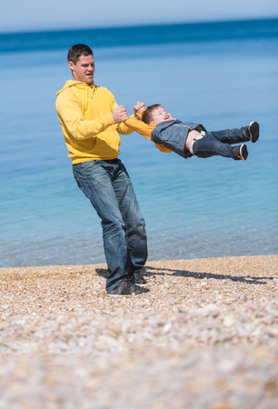 Father and son playing on the beach at the day time. Concept of friendly family.の写真素材