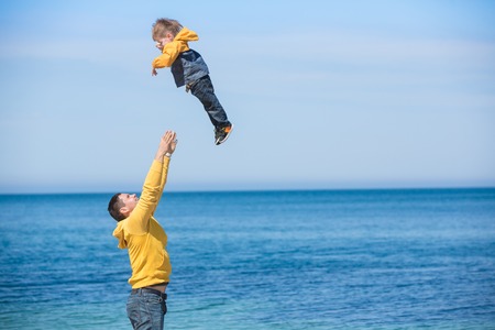 Father and son playing on the beach at the day time. Concept of friendly family.の写真素材