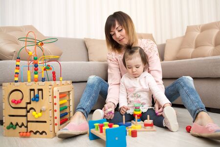 Mother and daughter indoors playing wooden toysの写真素材