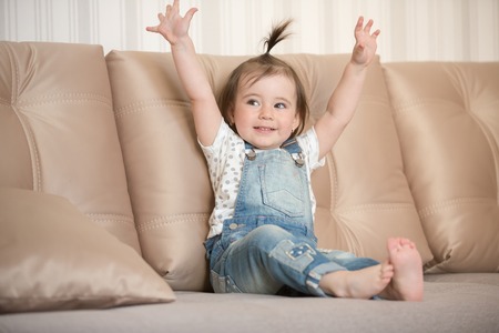 Little cute toddler girl sitting on the sofaの写真素材
