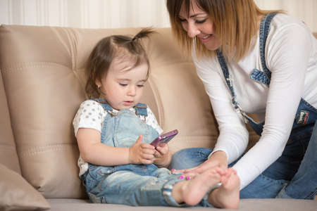 Mother and daughter indoors playing with smartphone