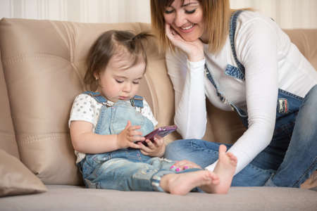Mother and daughter indoors playing with smartphone
