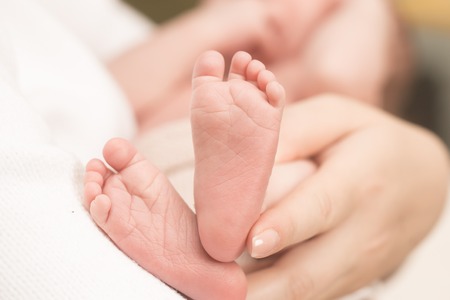 Baby feet in mother hands. Mom and her Child. Happy Family concept. Beautiful conceptual image of Maternityの写真素材