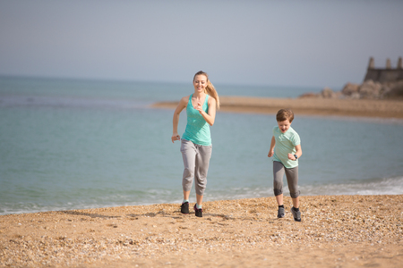 Mother with son running on the beach at morningの写真素材