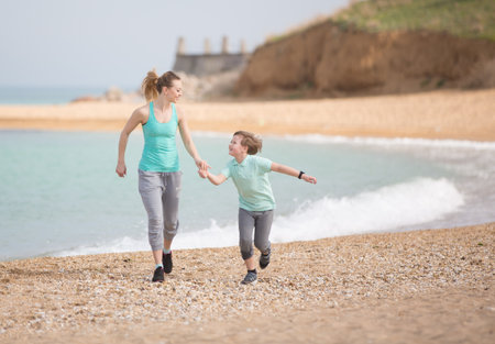 Mother with son running on the beach at morningの写真素材